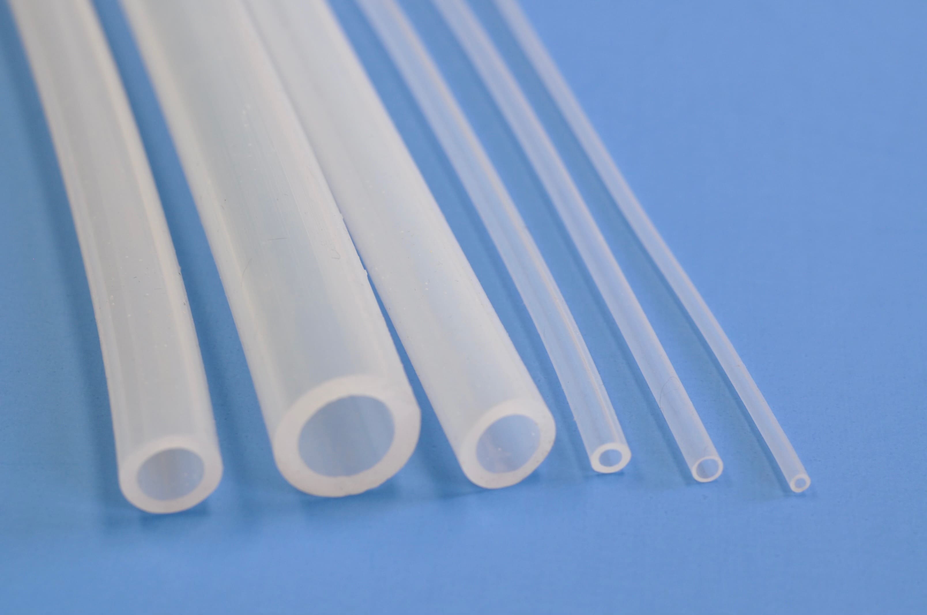 Six clear silicone tubes aligned side-by-side. Each tube is a different size.