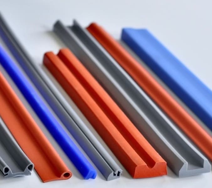 Assorted silicone rubber parts of varying colors and profile shapes resting side-by-side