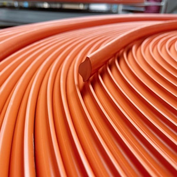 Image of neatly-coiled, extruded, red silicone rubber that is shaped like a saucer