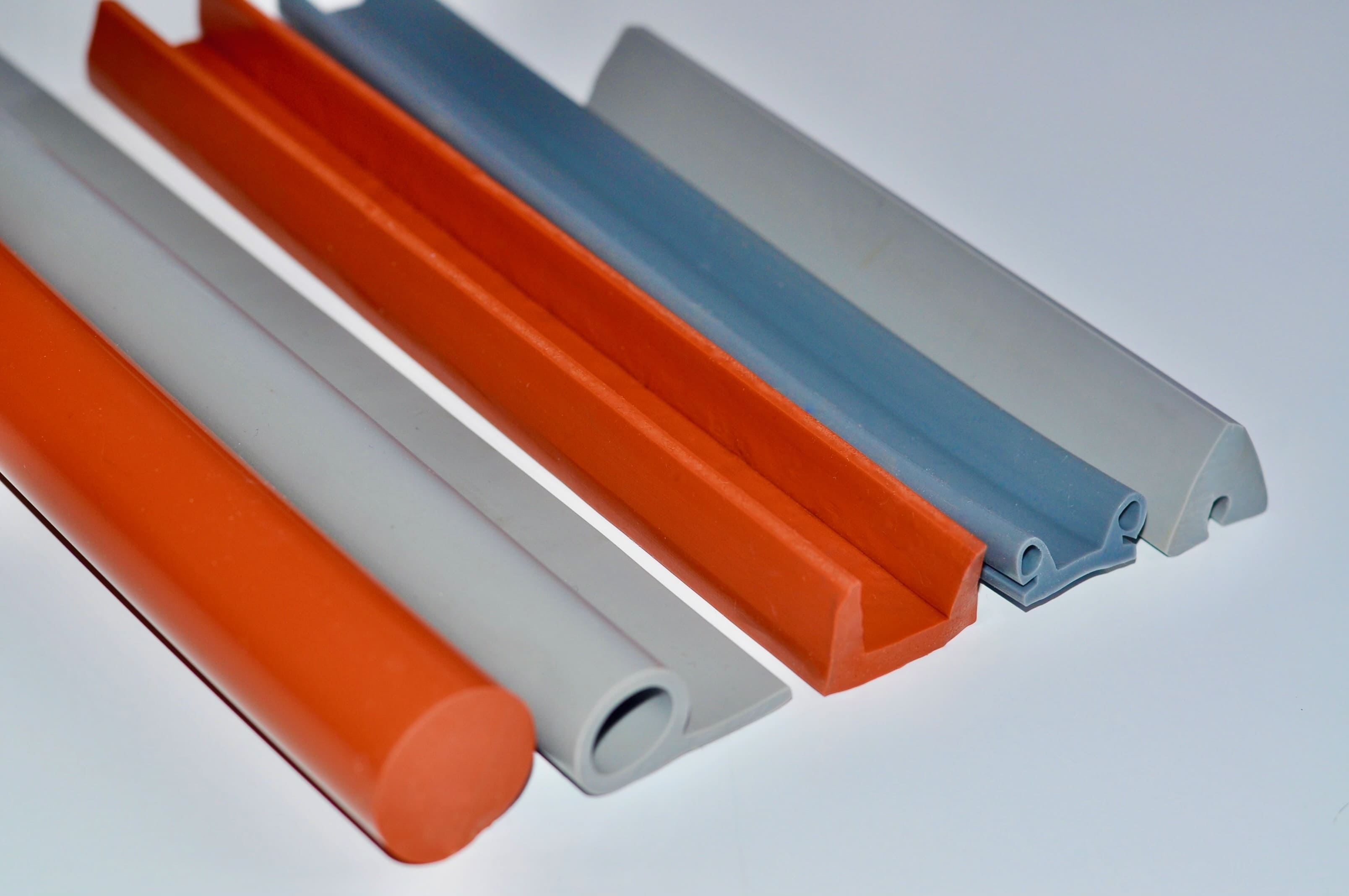 Assorted silicone rubber parts of varying colors and profile shapes resting side-by-side